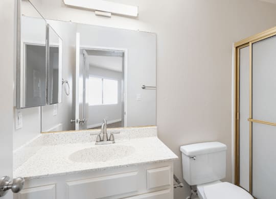 a bathroom with a toilet and a sink and a mirror at Huntington Terrace North Senior, Huntington Beach, CA