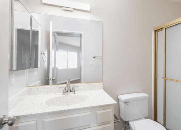 a bathroom with a toilet and a sink and a mirror at Huntington Terrace North Senior, Huntington Beach, CA