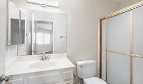 a bathroom with a toilet and a sink and a mirror at Huntington Terrace North Senior, Huntington Beach, CA