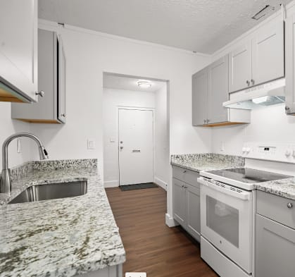 a kitchen with white cabinets and granite counter tops and white appliances