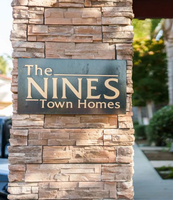 a stone column with a sign that reads the nines town homes