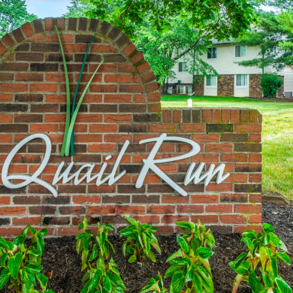a brick sign in front of a garden