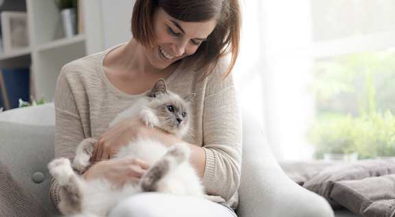 A woman is sitting on a chair holding a cat.