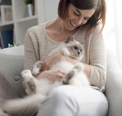 A woman is sitting on a chair holding a cat.