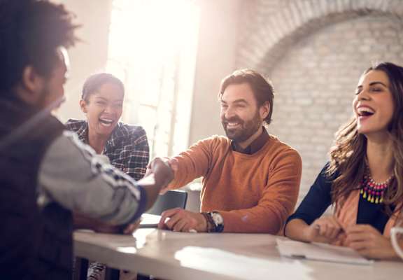 Four people are sitting around a table, laughing and enjoying each other's company.
