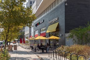 people sitting at tables outside of a restaurant on a sidewalk
