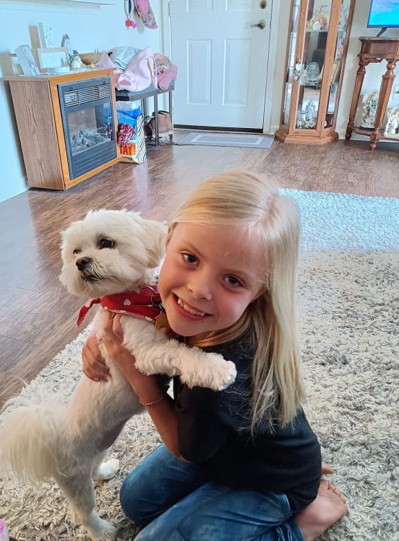 a little girl holding a small white dog