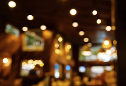 A blurry image of a restaurant with lights on the ceiling.