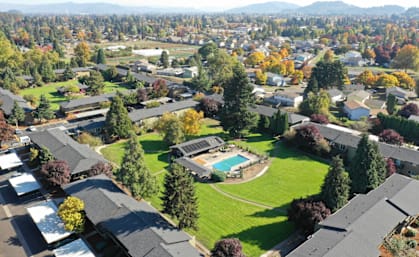 an aerial view of a neighborhood with houses and a green lawn and a pool