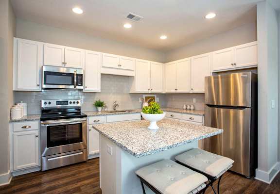 A kitchen with a granite countertop and stainless steel appliances.