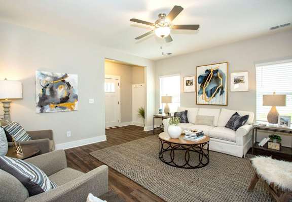 A living room with a grey couch, a coffee table, and a painting on the wall.