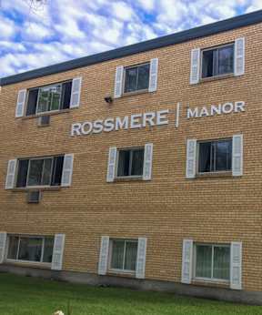 A brick building with the words Rossmere Manor on the side.