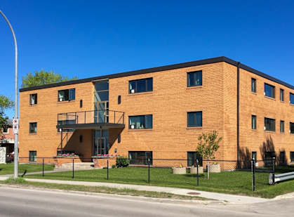 A red brick building with a black fence in front.