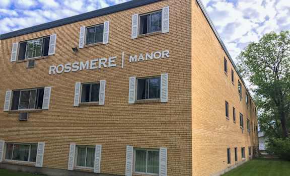 A brick building with the words Rossmere Manor on the side.
