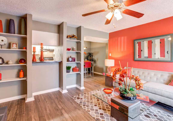 a living room with orange walls and a ceiling fan