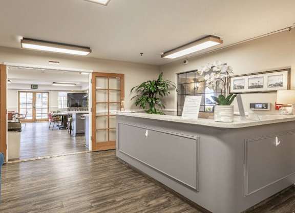 a reception area with a blue couch and a counter in a lobby at Huntington Terrace North Senior, Huntington Beach, CA
