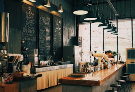 A restaurant interior with a long bar and a menu board on the wall.