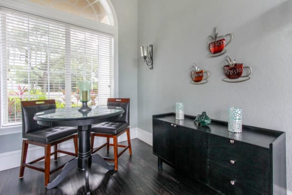 Clubhouse Seating Area with Dining Table and Chairs in Front of Window Next to Black Buffet with Decorations