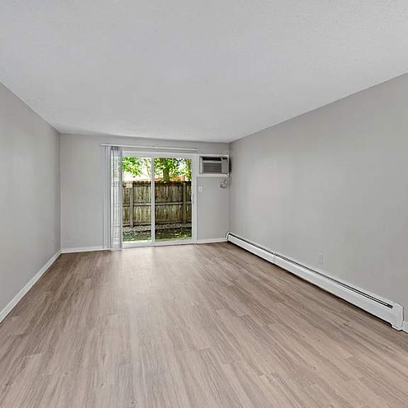 A room with light wood flooring and white walls.