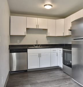 an empty kitchen with stainless steel appliances and white cabinets