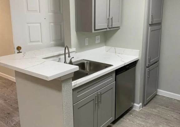 A kitchen with a white counter top and grey cabinets at Brook Meadow Village Apartments , Austin, TX, 78758