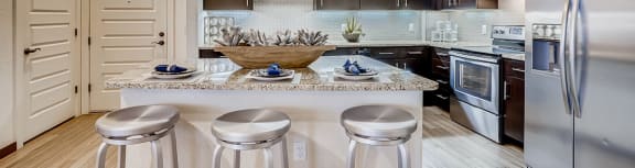 a fire pit on a rooftop patio with a view of the city in the background at Waterford RiNo Apartments, Colorado