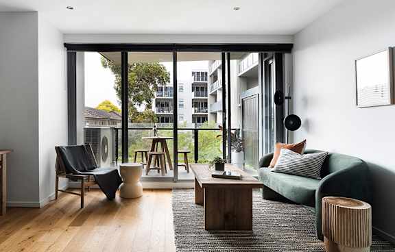 a living room with a green couch and a balcony