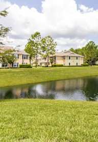 a fountain in the middle of a pond with houses in the background