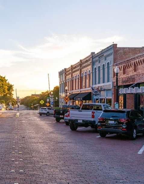 Cars parked on a brick road with buildings on either side.