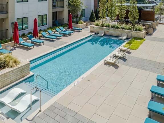 A swimming pool surrounded by lounge chairs and umbrellas.