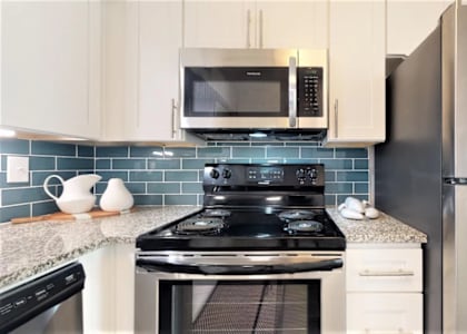 A kitchen with a black stove top oven and a black microwave above it. at Cumberland Pointe, Smyrna, Georgia