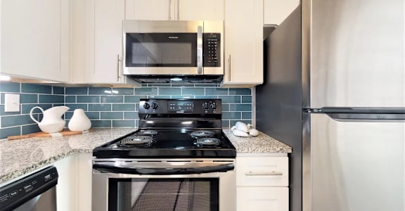 A kitchen with a black stove top oven and a black microwave above it. at Cumberland Pointe, Smyrna, Georgia
