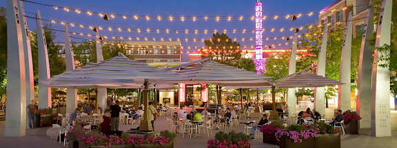 A restaurant with tables and chairs under a canopy with string lights hanging above.