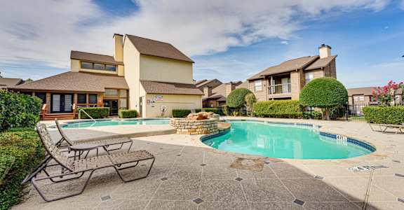 a swimming pool with a bench next to it and a house in the background