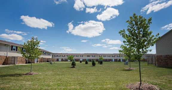 A grassy field with trees and a building in the background.