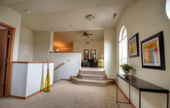 a living room with stairs and a ceiling fan