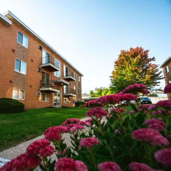 a brick building with grass and flowers in front of it