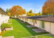 Thumbnail 8 of 8 - A row of houses with green lawns and trees in the background.