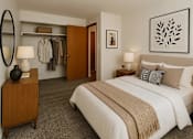 Thumbnail 1 of 8 - A bedroom with a large bed and a clothing rack.