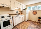Thumbnail 6 of 8 - A kitchen with white appliances and wooden floors.