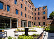 Thumbnail 6 of 8 - a courtyard with seating and a fountain in front of a red brick building
