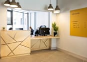 Thumbnail 3 of 8 - a reception desk with a yellow poster on the wall