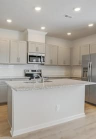 A kitchen with a white island and stainless steel appliances.