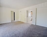 an empty living room with white walls and carpet