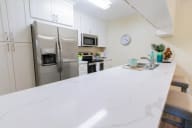 a white kitchen with stainless steel appliances and a counter top