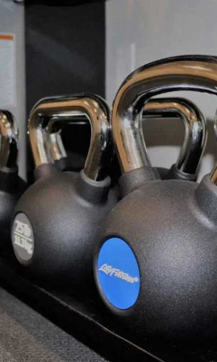 A set of kettlebells with a blue logo on them are on a rack.