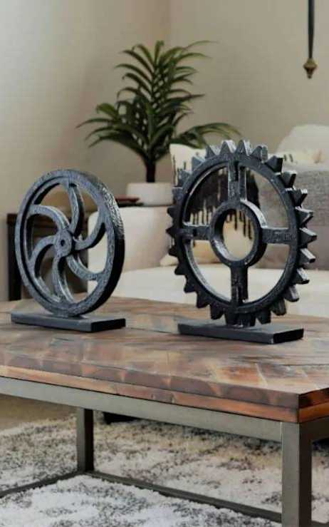 Two black gear sculptures on a wooden table.