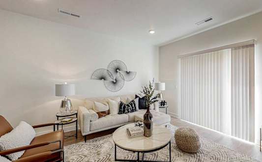 A modern living room with a white sofa, a round coffee table, and a large abstract wall art.