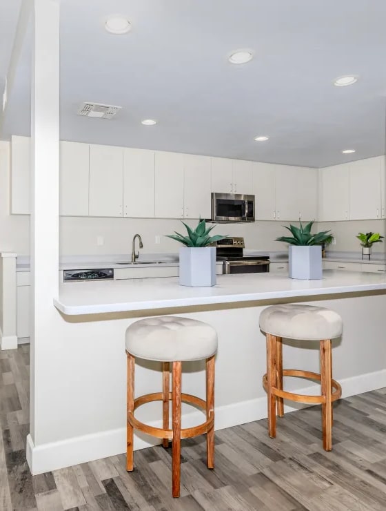 A kitchen with white cabinets and a wooden floor.