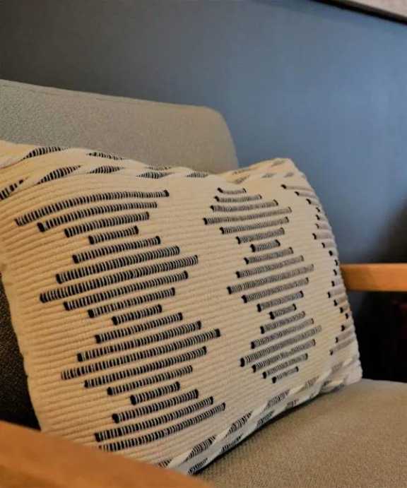 A couch with a patterned pillow sits in a room with a wooden side table.